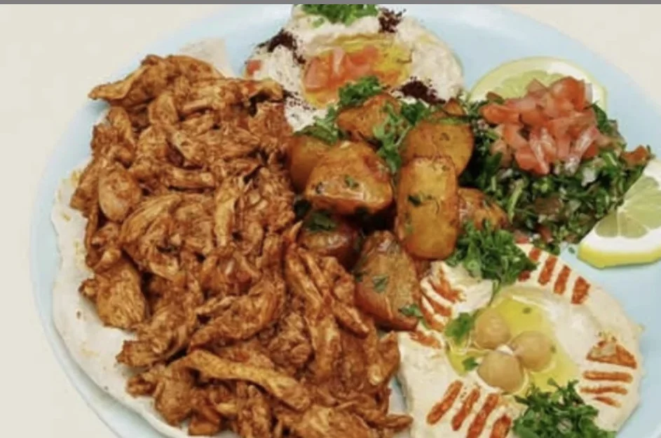 Assiette garnie de poulet mariné, frites maison, hommos et taboulé