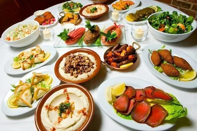 Table garnie de mezzés libanais froids et chauds : hommos, moutabal, falafels, feuilles de vigne, kebbés et crudités
